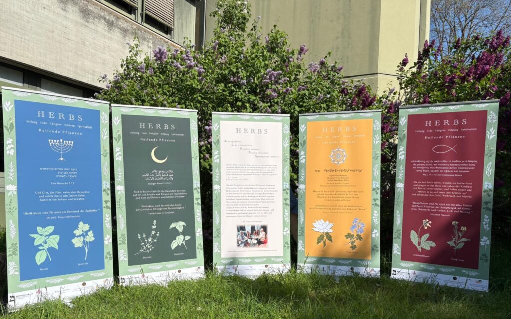 5 Poster stehen auf der Wiese. Alle haben den Titel HERBS. Gestaltet 5 unterschiedlichen Religionen in 5 unterschiedlichen Farben . 